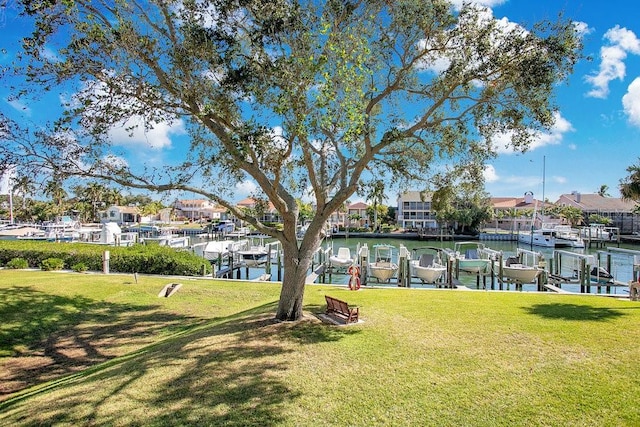 view of green lawn featuring a boat dock, a residential view, and boat lift
