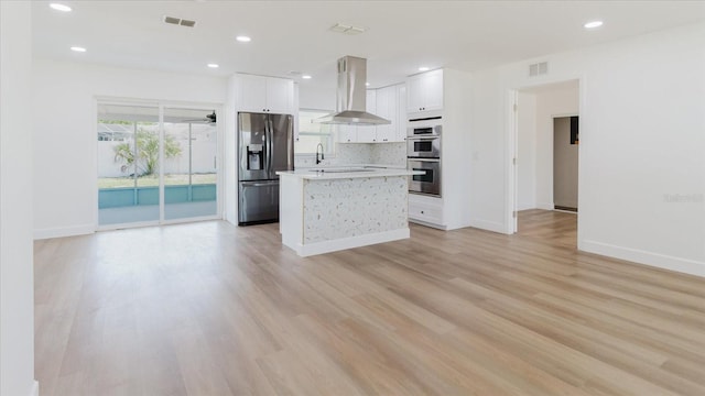 kitchen with appliances with stainless steel finishes, extractor fan, light countertops, white cabinets, and a center island