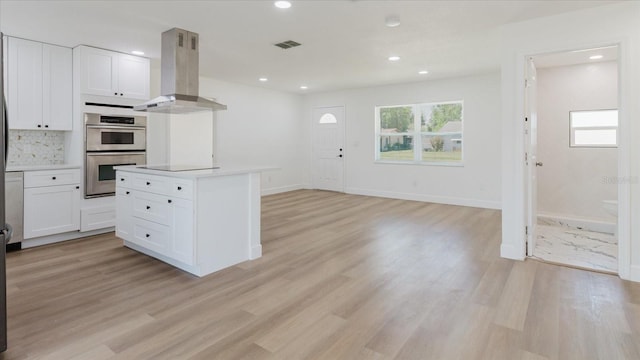 kitchen featuring range hood, white cabinets, light wood-type flooring, and recessed lighting