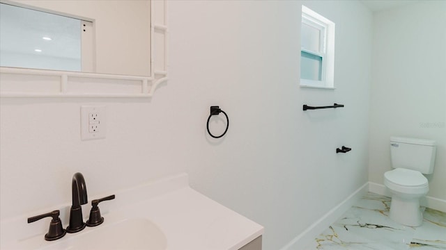 bathroom with toilet, baseboards, marble finish floors, and vanity
