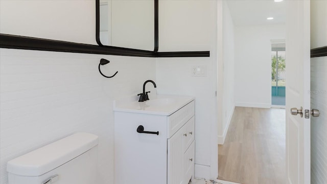 bathroom featuring vanity, toilet, wood finished floors, and baseboards
