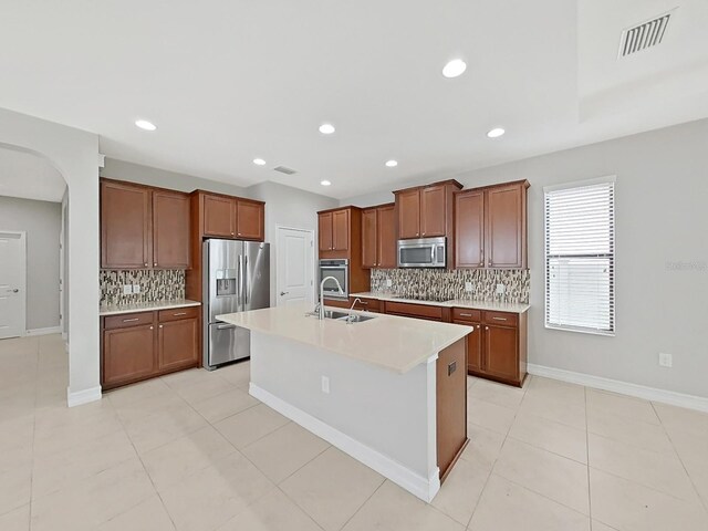 4063 Medicci Ln, Wesley Chapel, FL 33543 - kitchen with appliances with stainless steel finishes, a sink, backsplash, arched walkways, and brown cabinets