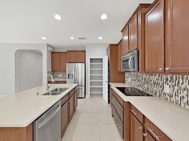 4063 Medicci Ln, Wesley Chapel, FL 33543 - kitchen featuring a sink, stainless steel appliances, backsplash, arched walkways, and light tile patterned floors