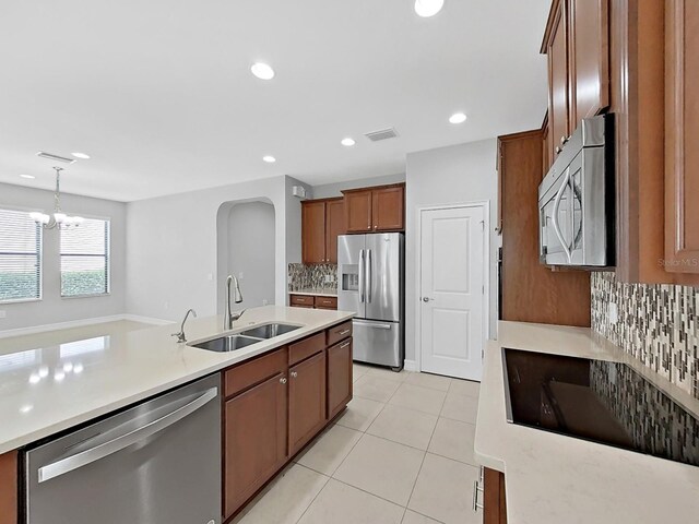 4063 Medicci Ln, Wesley Chapel, FL 33543 - kitchen featuring stainless steel appliances, a sink, light tile patterned floors, backsplash, and light countertops