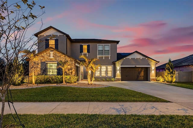 traditional-style house with stone siding, driveway, an attached garage, stucco siding, and a front yard