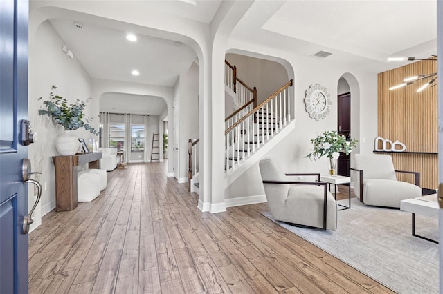 entryway with arched walkways, wood finished floors, stairs, baseboards, and recessed lighting