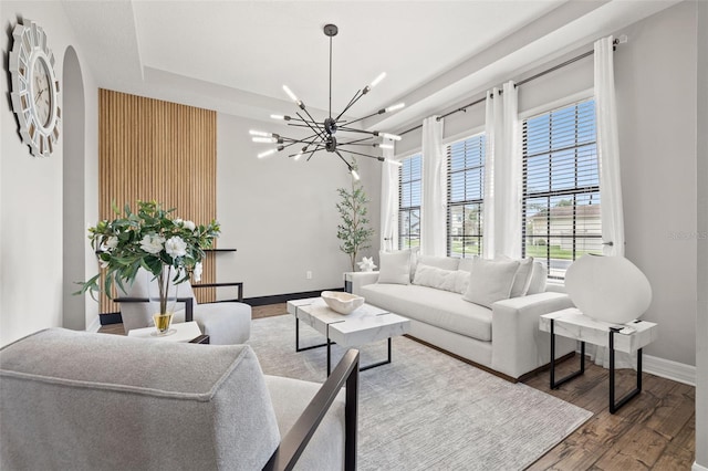 living room with a chandelier, baseboards, wood finished floors, and a raised ceiling