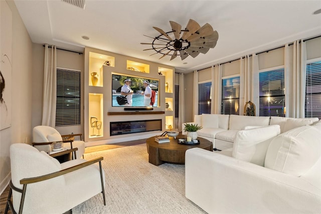living area with baseboards, a glass covered fireplace, and wood finished floors