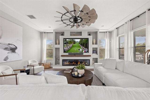 living room featuring wood finished floors, plenty of natural light, baseboards, and a glass covered fireplace