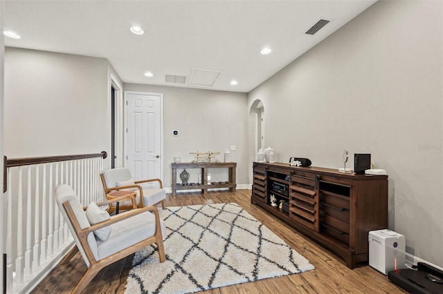 sitting room with wood finished floors, recessed lighting, baseboards, and arched walkways