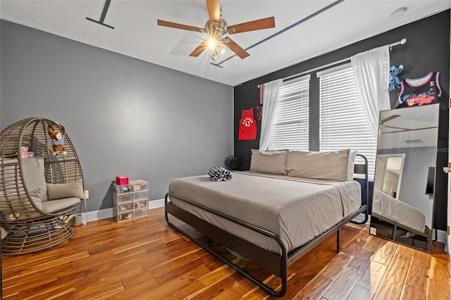 bedroom with wood finished floors, baseboards, and a ceiling fan