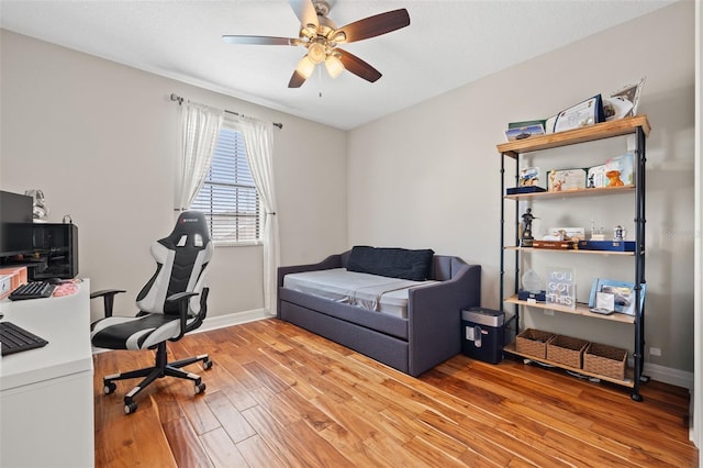 office area with a ceiling fan, light wood finished floors, and baseboards