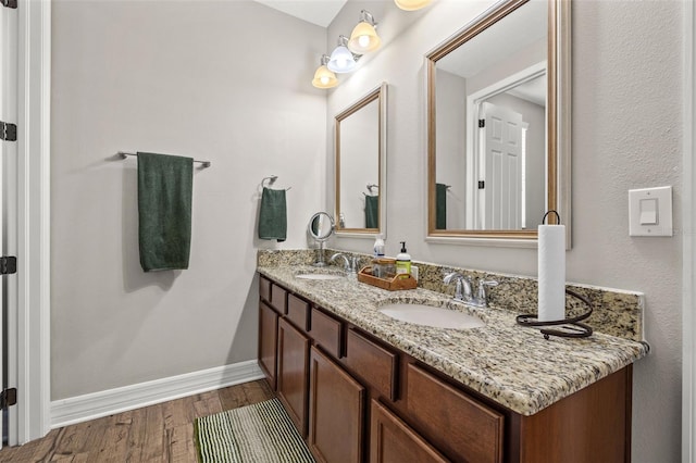 full bath featuring wood finished floors, baseboards, and double vanity