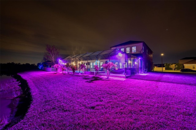 back of house at night featuring a lanai