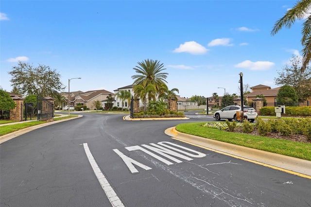 view of asphalt street featuring street lighting, a residential view, and curbs