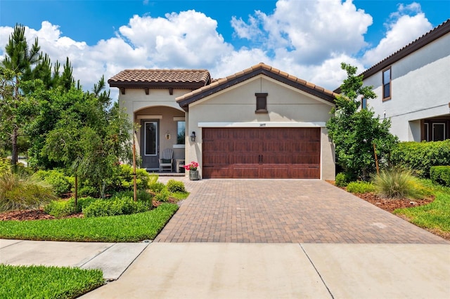 3877 Burdick Loop, Odessa, FL 33556 - mediterranean / spanish-style house featuring decorative driveway, an attached garage, a tile roof, and stucco siding