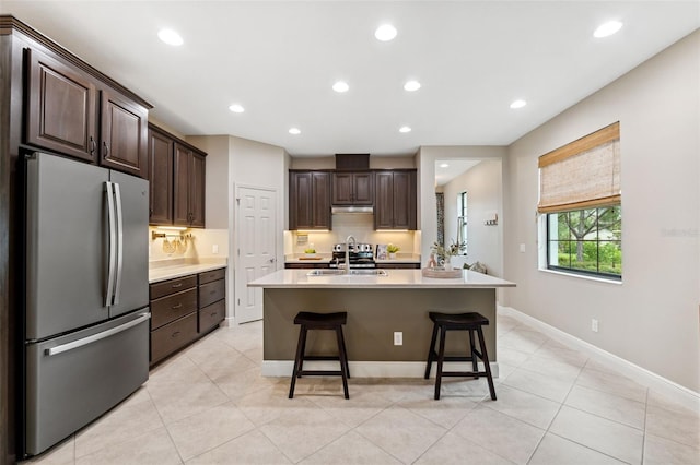 3877 Burdick Loop, Odessa, FL 33556 - kitchen featuring freestanding refrigerator, light countertops, dark brown cabinets, a breakfast bar, and light tile patterned floors