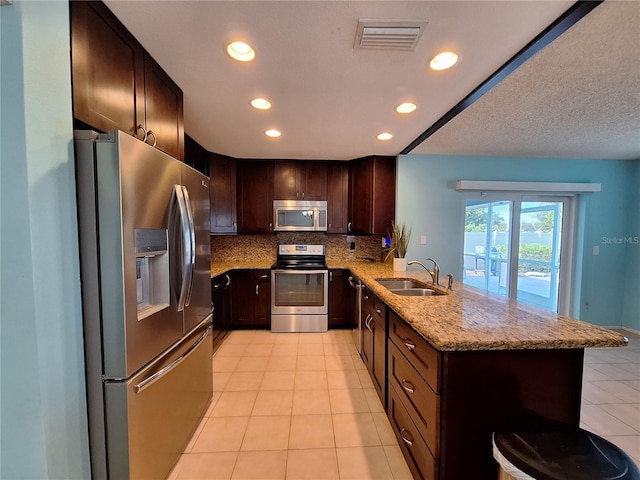 3357 Hunt Club Dr, Clearwater, FL 33761 - kitchen featuring stainless steel appliances, a sink, a peninsula, light tile patterned floors, and light stone counters
