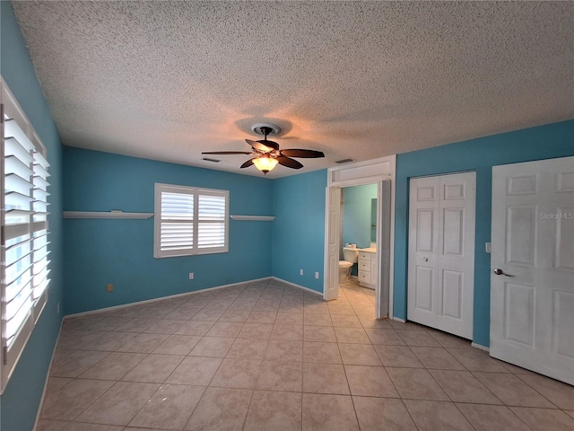 3357 Hunt Club Dr, Clearwater, FL 33761 - unfurnished bedroom featuring a textured ceiling, light tile patterned floors, ceiling fan, ensuite bath, and baseboards