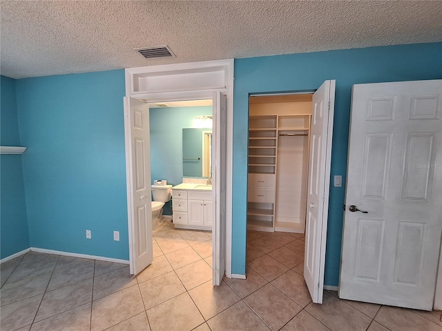 3357 Hunt Club Dr, Clearwater, FL 33761 - unfurnished bedroom with light tile patterned floors, a closet, a textured ceiling, baseboards, and a sink