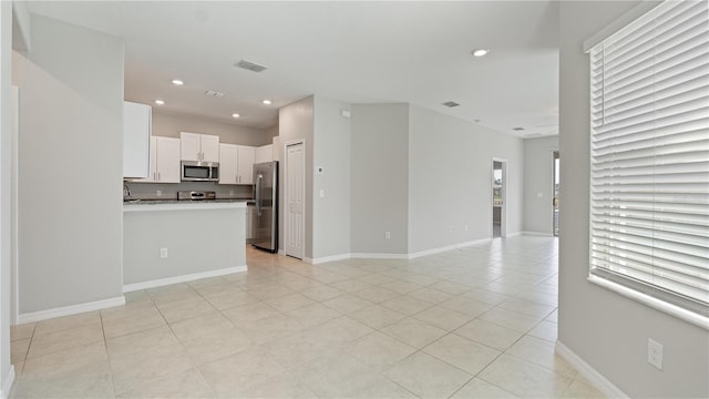 unfurnished living room featuring light tile patterned floors, recessed lighting, and baseboards