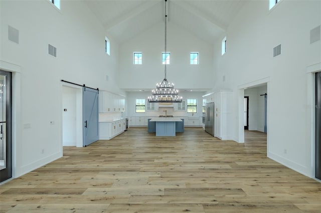 3515 Powerline Rd, Lithia, FL 33547 - unfurnished living room with a barn door, high vaulted ceiling, light wood-style floors, a chandelier, and a sink