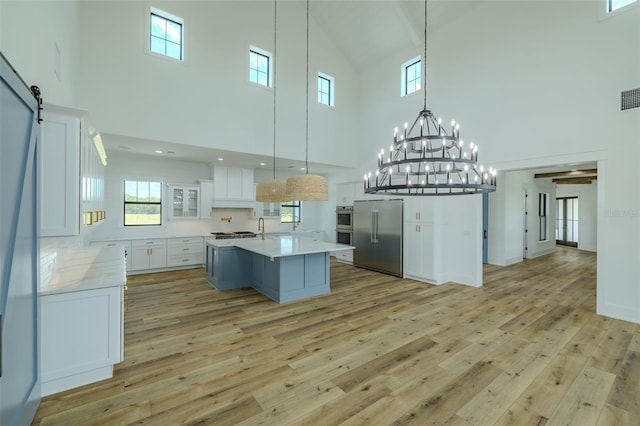 3515 Powerline Rd, Lithia, FL 33547 - kitchen featuring stainless steel appliances, high vaulted ceiling, light wood-style flooring, white cabinetry, and pendant lighting