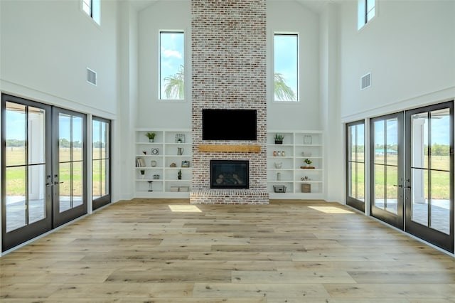 3515 Powerline Rd, Lithia, FL 33547 - unfurnished living room featuring french doors, high vaulted ceiling, plenty of natural light, a fireplace, and light wood-style flooring