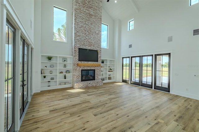 3515 Powerline Rd, Lithia, FL 33547 - unfurnished living room with high vaulted ceiling, french doors, light wood finished floors, a brick fireplace, and beamed ceiling
