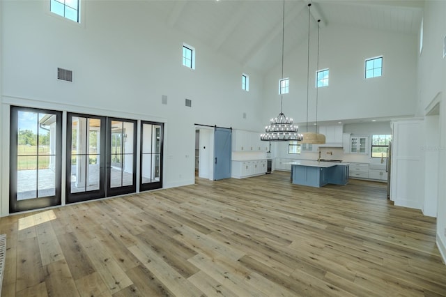 3515 Powerline Rd, Lithia, FL 33547 - unfurnished living room featuring high vaulted ceiling, a barn door, light wood-type flooring, a chandelier, and beamed ceiling