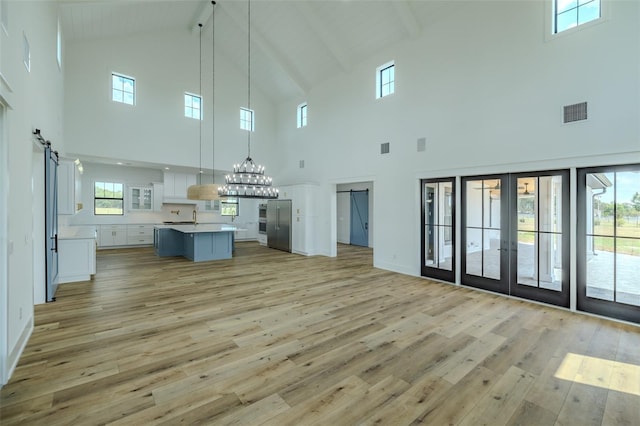 3515 Powerline Rd, Lithia, FL 33547 - unfurnished living room featuring high vaulted ceiling, a barn door, light wood finished floors, french doors, and beamed ceiling