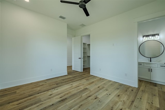 3515 Powerline Rd, Lithia, FL 33547 - unfurnished bedroom with light wood finished floors, baseboards, a walk in closet, ensuite bathroom, and ceiling fan
