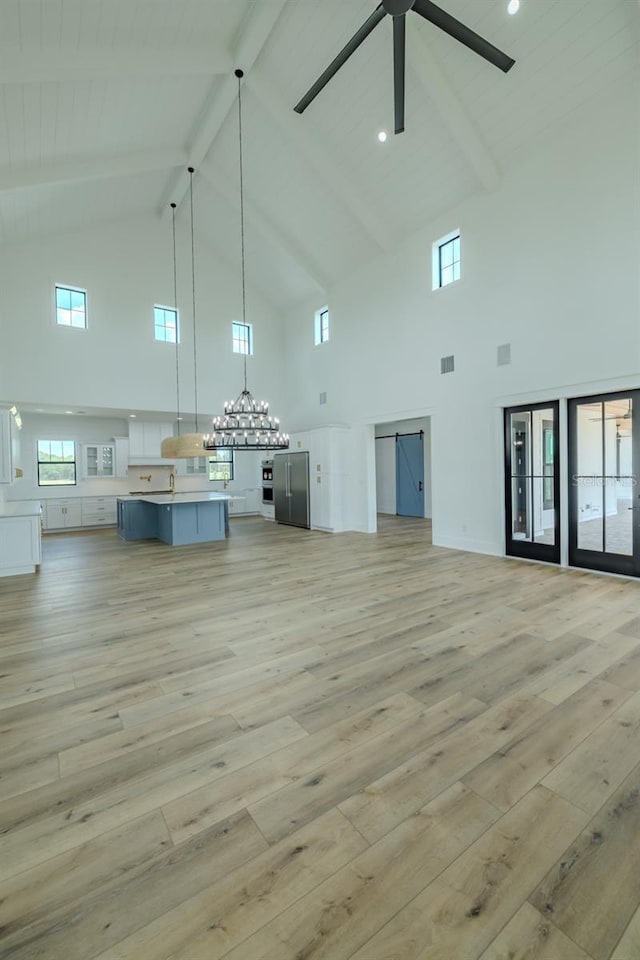 3515 Powerline Rd, Lithia, FL 33547 - unfurnished living room with high vaulted ceiling, light wood-style floors, beam ceiling, a chandelier, and a ceiling fan