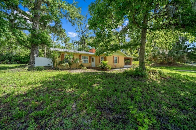 10170 W Yulee Dr, Homosassa, FL 34448 - ranch-style house with a front yard, a chimney, a standing seam roof, and a metal roof