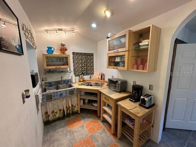 10170 W Yulee Dr, Homosassa, FL 34448 - kitchen featuring arched walkways, stainless steel stovetop, lofted ceiling, open shelves, and glass insert cabinets