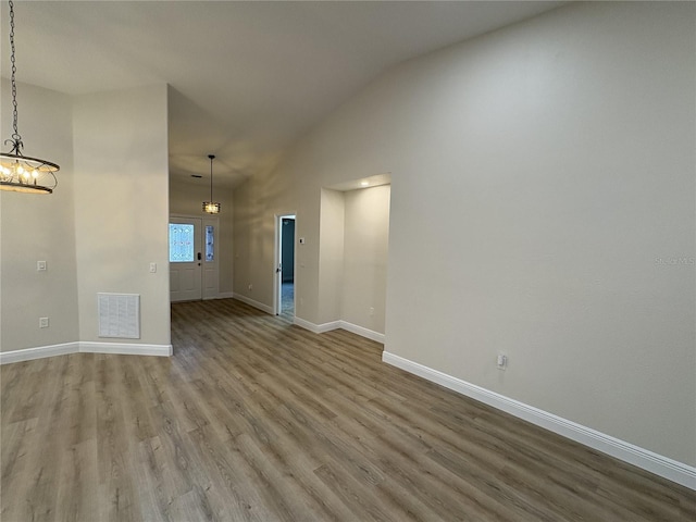 6533 Brentwood Dr, Zephyrhills, FL 33542 - unfurnished living room with a chandelier, wood finished floors, baseboards, and high vaulted ceiling