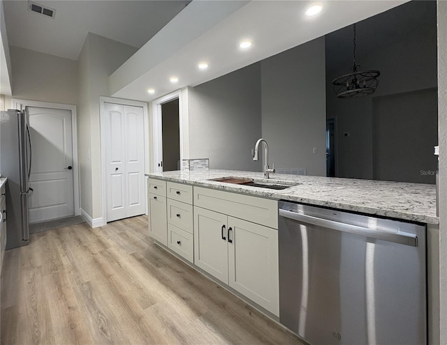 6533 Brentwood Dr, Zephyrhills, FL 33542 - kitchen featuring appliances with stainless steel finishes, a sink, white cabinetry, light stone countertops, and light wood-type flooring