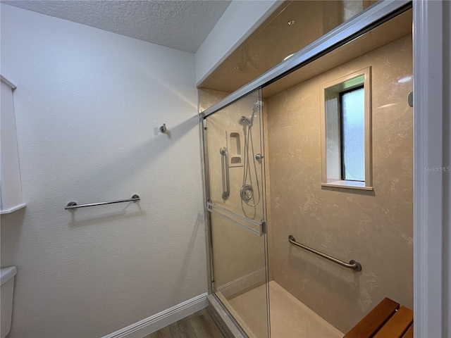 6533 Brentwood Dr, Zephyrhills, FL 33542 - bathroom featuring a shower stall, wood finished floors, toilet, a textured ceiling, and baseboards