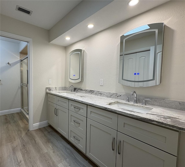 6533 Brentwood Dr, Zephyrhills, FL 33542 - bathroom with a stall shower, wood finished floors, double vanity, recessed lighting, and baseboards