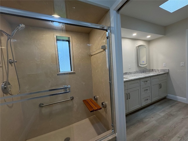 6533 Brentwood Dr, Zephyrhills, FL 33542 - bathroom with wood finished floors, a shower stall, double vanity, a skylight, and baseboards