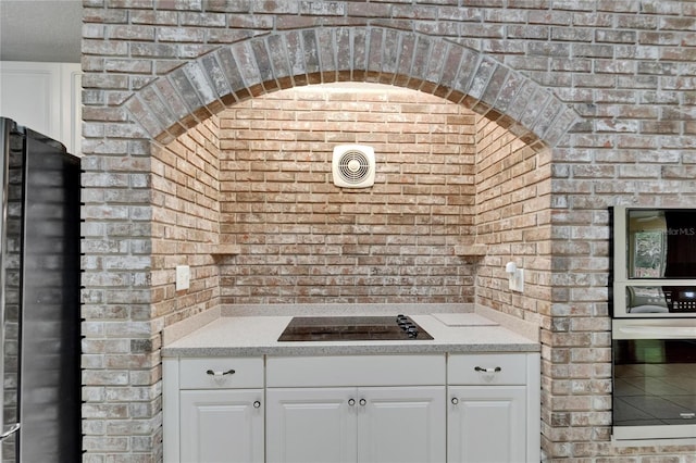 6801 Bishops Pointe Way, Riverview, FL 33578 - kitchen featuring freestanding refrigerator, black electric cooktop, brick wall, wine cooler, and white cabinetry