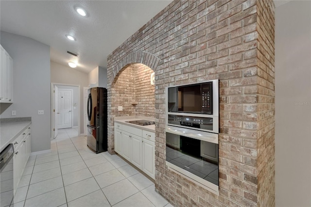 6801 Bishops Pointe Way, Riverview, FL 33578 - kitchen with black appliances, white cabinetry, light countertops, lofted ceiling, and brick wall