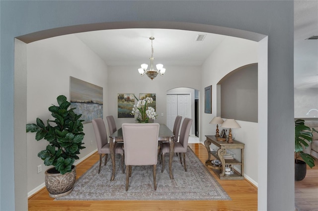6801 Bishops Pointe Way, Riverview, FL 33578 - dining space with arched walkways, wood finished floors, and a chandelier