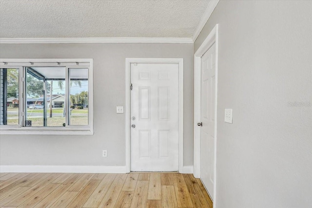 foyer with wood finished floors, ornamental molding, a textured ceiling, and baseboards