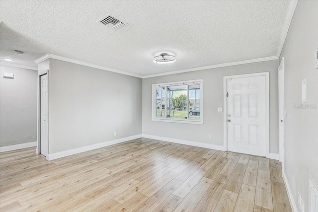 foyer featuring light wood finished floors, a textured ceiling, crown molding, and baseboards