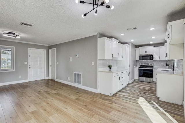 kitchen featuring appliances with stainless steel finishes, a sink, a textured ceiling, decorative backsplash, and crown molding