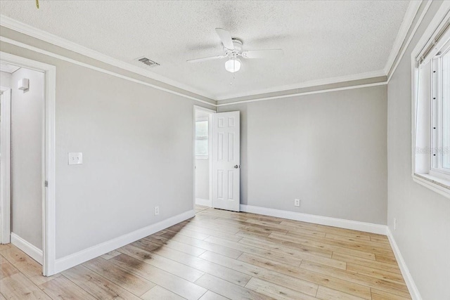 empty room with a textured ceiling, a ceiling fan, wood finished floors, plenty of natural light, and ornamental molding