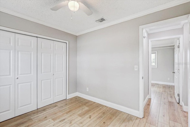 unfurnished bedroom featuring light wood-style floors, a textured ceiling, a closet, ornamental molding, and baseboards