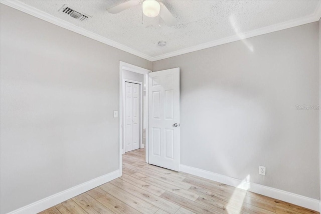 unfurnished room featuring a textured ceiling, light wood finished floors, baseboards, ceiling fan, and ornamental molding