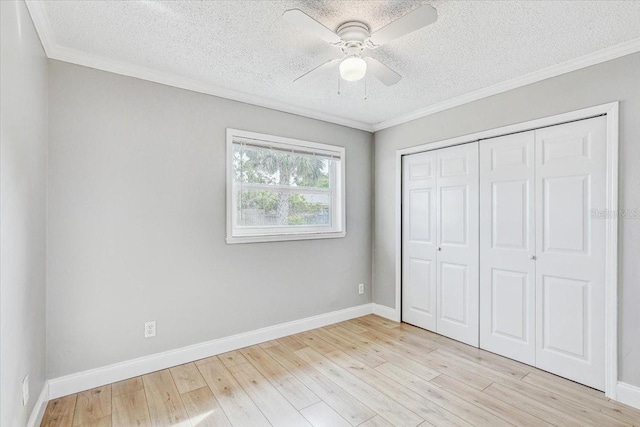 unfurnished bedroom with a textured ceiling, light wood-style flooring, a closet, baseboards, and ornamental molding